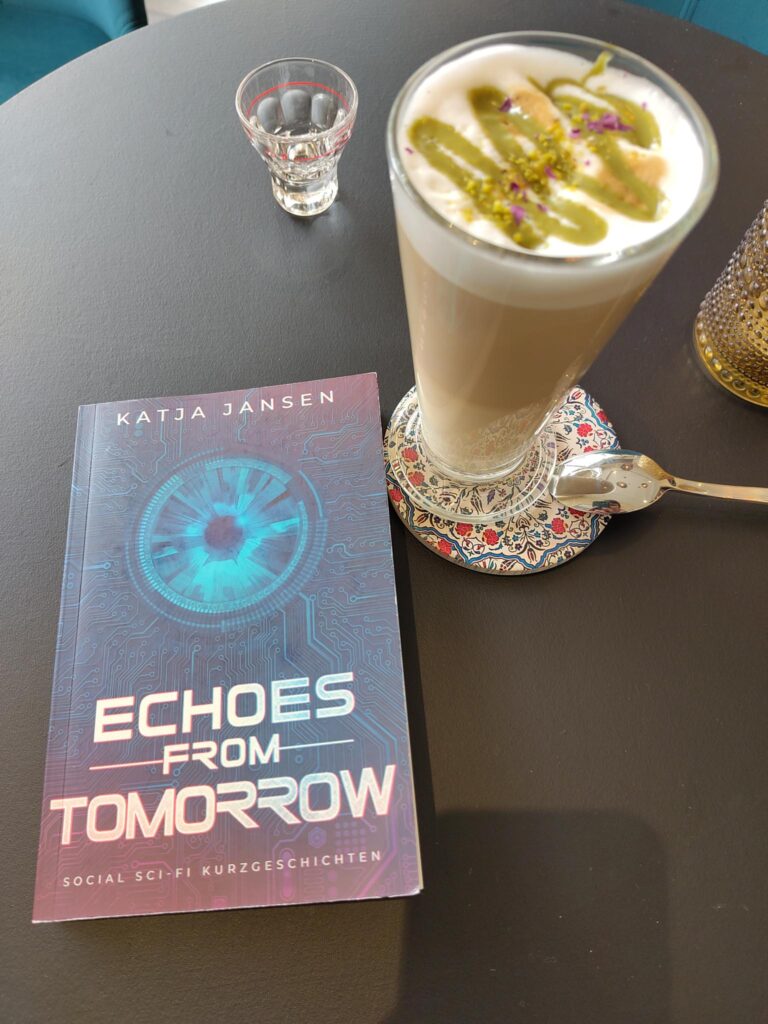Das Buch "Echoes from Tomorrow" liegt auf einem Tisch neben einem Glas Latte Macchiato.
