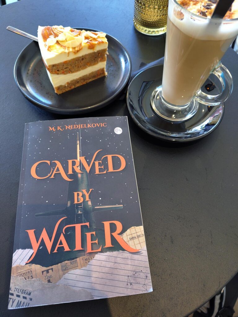Foto von "Carved by Water" neben Kaffee und Kuchen
