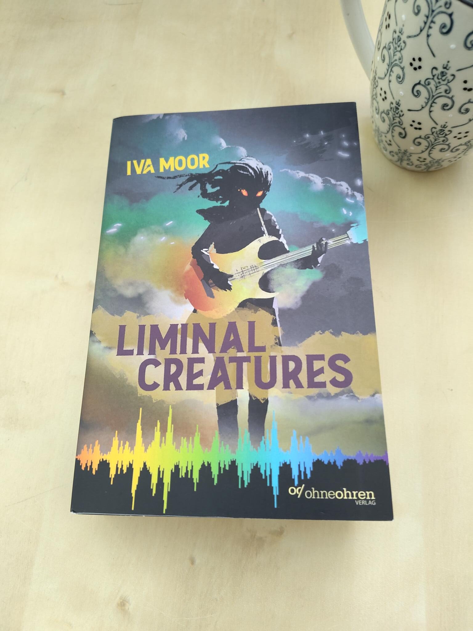 Foto vom Buch "Liminal Creatures" neben einer Tasse